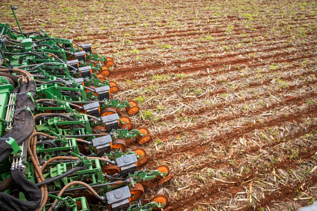 Fotografia colorida mostrando tratores em uma plantação de soja.